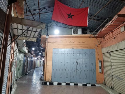 Medina during Ramadan Empty market alley at night with locked shops and a Moroccan flag, Morocco
