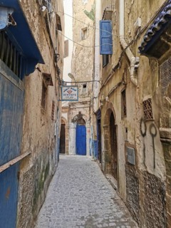 Narrow old town alleyway with weathered doors and the sign of a dentist, dentist, under a blue sky,