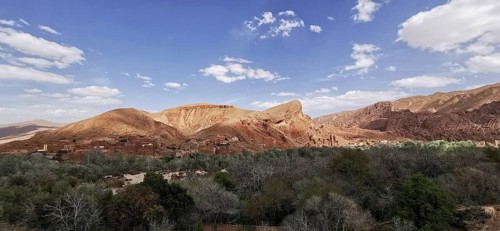 Wide desert landscape with mountains under a slightly cloudy sky, Morocco