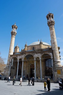Impressive mosque with minarets against a blue sky with passers-by in the foreground, Aziziye