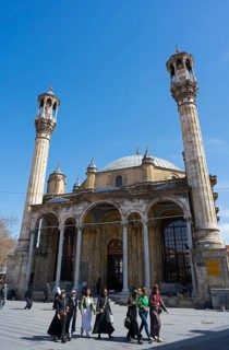 Historic mosque with distinctive minarets and people on the square in front of it, Aziziye Mosque,