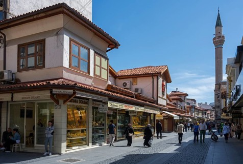 Bustling market street with traditional shops and a minaret in the background, Konya, Central