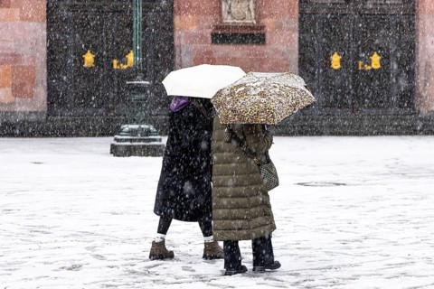 Two passers-by walk across Frankfurt's Römerberg with umbrellas. Heavy snowfalls have caused