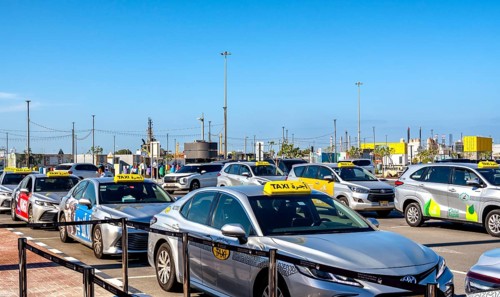 Taxi and hop on hop off buses are waiting for tourists in the cruise terminal parking lot, Abu