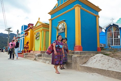 Mayan woman wearing traditional clothing at colorful graves at the cemetery in Chichicastenango,