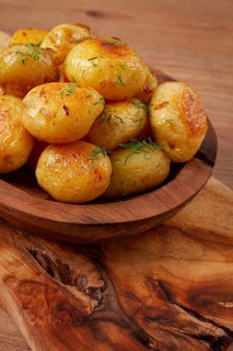 Baked new potatoes, with butter and dill, on a wooden plate, homely, rustic, no people
