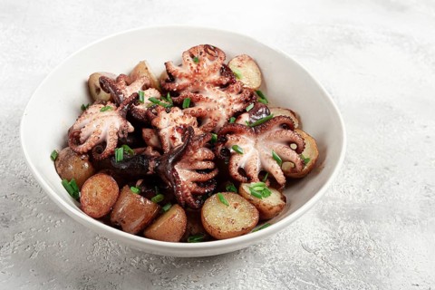 Baby grilled octopus with golden baked potatoes and fresh herbs, Maltese cuisine, homemade, no