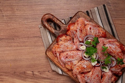Chicken wings, marinated and laid out on a wooden platter, ready for cooking, grilling or baking,