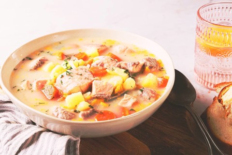 A bowl of soup on a light background, Finnish fish soup, lohikeito soup, creamy fish soup
