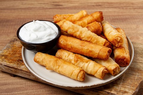 Fried spring rolls with cheese, on a wooden background, with cream sauce, no people