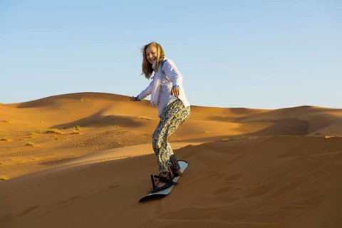 Young woman with snowboard in the sand dunes, near Merzouga, Meknès-Tafilalet region, Erg Chebbi,