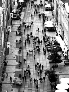 Black and white aerial view of a busy pedestrian zone with numerous passers-by and cafés, Gdansk,