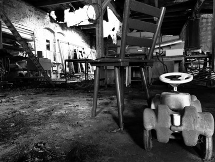 Abandoned industrial space with an old chair and a toy car on the floor, black and white, Upper