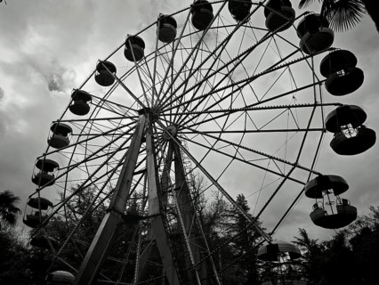 Silhouette of a Ferris wheel against a cloudy sky in a black and white theme park, Kutaisi, Georgia