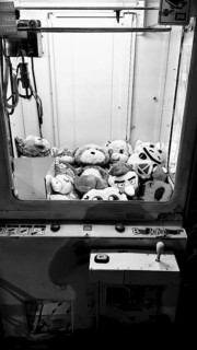 View of a claw machine filled with stuffed animals in a play area, black and white, Batumi, Georgia