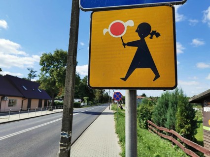 Road sign depicting a stylized person holding a candy on a sunny day, Poland
