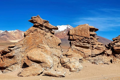 Majestic rock formations in a vast, barren desert landscape under blue skies, The Altiplano