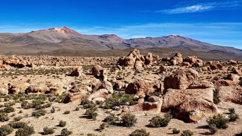 Rocky desert landscape with impressive rock formations and mountains under a blue sky, The