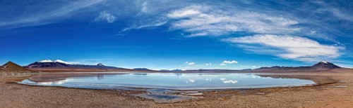 Wide and open landscape with a lake under dramatic skies and distant mountains, The Laguna Colorada