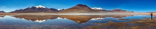 Wide panorama of mountains with reflecting lake and clear sky above the scene, Laguna Colorada in