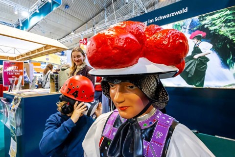 Tradition and progress. A young trade fair visitor wearing 3D glasses next to a model of a woman