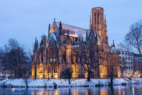 March 18, 2018, winter dusk with snow, illuminated lake and Gothic church Johanneskirche, calm