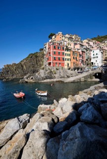 Colourful houses under blue sky, view of the fishing village of Riomaggiore, boats in the harbour,