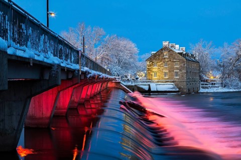 Illuminated Moulin Neuf water flow control dam and walkway over Des Mille-Iles river plus New Mill
