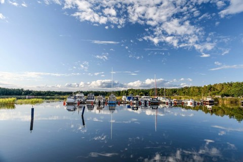 Several boats are moored in the quiet pleasure boat harbor of Ekenäs, water reflects the sky,