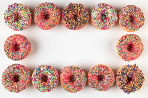 Donut frame with colorful sprinkles on white background