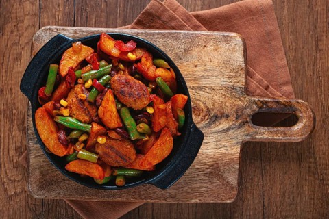 Steakhouse pfanne, fried potato slices, with meatballs, and vegetable mixture, on a black plate