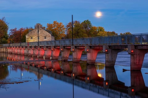 Illuminated Moulin Neuf water flow control dam and walkway over Des Mille-Iles river plus New Mill