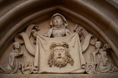 Woman in medieval clothing holding cloth with the face of Christ, stone figure, choir room,