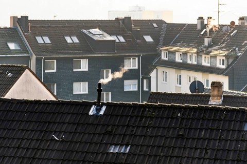 Smoke plume from a chimney over densely built residential area in the evening light, wintry city