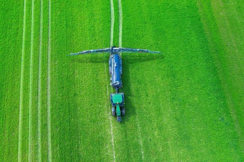 Aerial view over tractor towed liquid manure spreader, slurry spreader enabling the fertilization