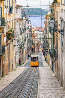 Traditional vintage yellow tram on tram line 28 climbing steep cobbled street in the capital city