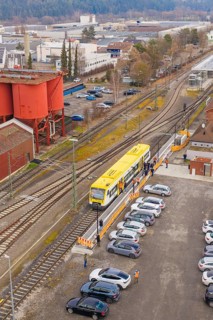 Aerial view of a train station with a yellow train surrounded by parking lots and industrial