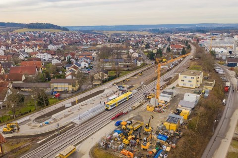 Aerial view of urban construction site with yellow train on tracks and residential buildings,