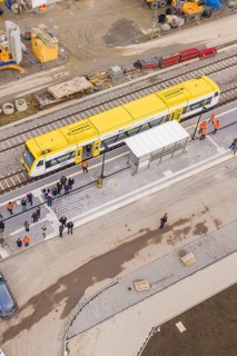 A bird's eye view of a yellow train at a train station with people, taking the Hermann Hesse