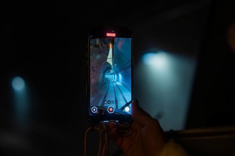 A smartphone shows a picture of a tunnel with rails, the Hermann Hesse Railway, Calw, Black Forest,