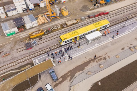 Bird's eye view of a train station with a yellow train and working people, bus ride taken by the