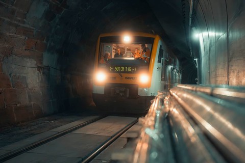 A modern train passes through an illuminated tunnel at night, taking the Hermann Hesse Railway,
