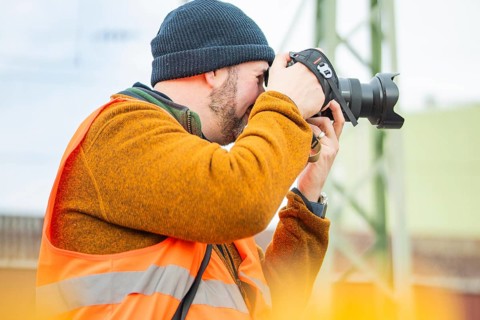 A photographer wears a safety vest and takes pictures at work, taking the Hermann Hesse Railway,