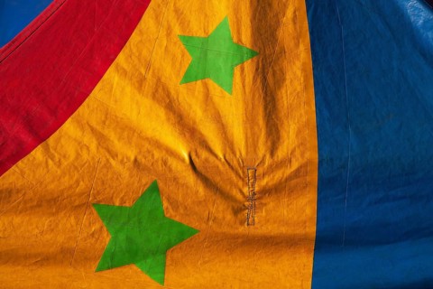 Close-up of two green stars on dyed red, yellow and blue canvas cloth material, Quebec, Canada