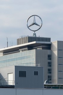 Industrial building with Mercedes-Benz logo on the roof under cloudy sky, Mercedes Star,