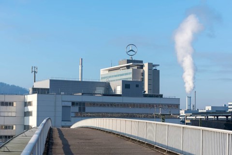 Building with Mercedes logo and rising steam in the background under a clear sky, Mercedes star,
