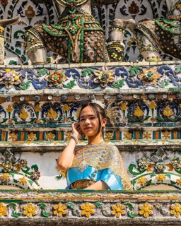 Young woman in traditional clothing presents herself to photographers, Wat Arun Buddhist temple,