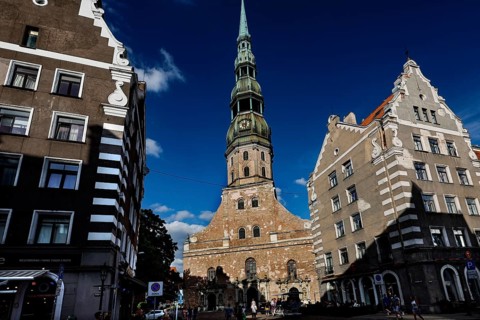 Gothic St. Peter's Church in Riga between historic buildings in sunlight, Riga, Latvia