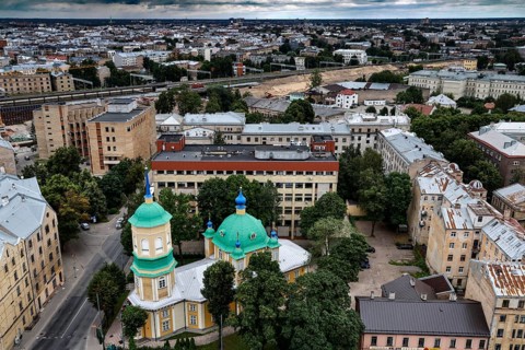 Annunciation of Our Lady in the midst of municipal buildings and green tree roofs, Riga, Latvia