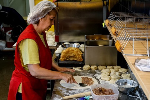 A woman prepares fresh chebureks at a stand at the Central Market in Riga, Riga, Latvia